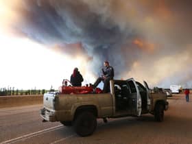 People wait at a road block as smoke rises from a wildfire near Fort McMurray, Alberta, Canada, on May 6, 2016 (Picture: Cole Burston/AFP via Getty Images)