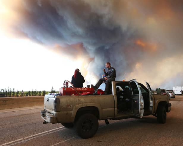 People wait at a road block as smoke rises from a wildfire near Fort McMurray, Alberta, Canada, on May 6, 2016 (Picture: Cole Burston/AFP via Getty Images)