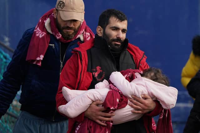 A man thought to be a refugee carries a small child after they were brought ashore by the RNLI at Dover, Kent, following a small boat incident in the English Channel (Picture: Gareth Fuller/PA Wire