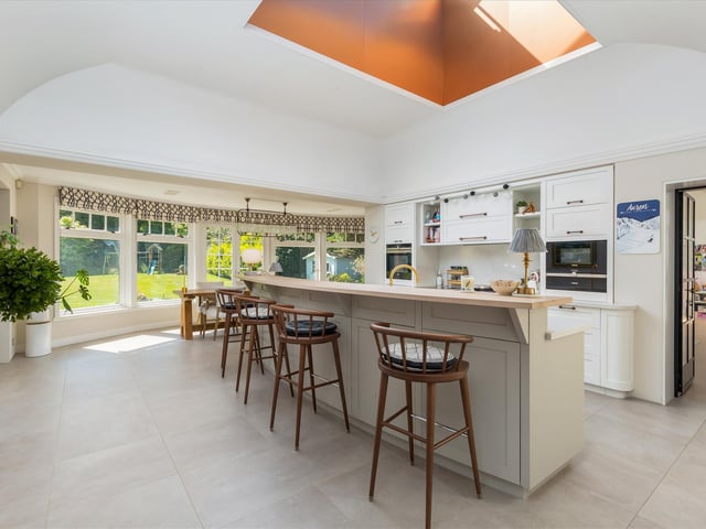 The kitchen is by Laurence McIntosh, with a delightful fan-shaped breakfast bar and solid wood units with white stone worktops.
