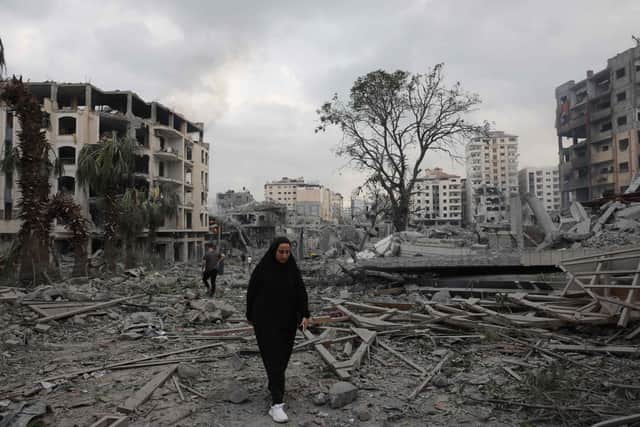 Palestinians walk through debris amid the destruction from Israeli airstrikes in Gaza City's al-Rimal neighbourhood (Photo by MOHAMMED ABED/AFP via Getty Images)
