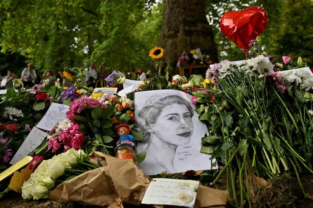 Members of the public look at flowers and tributes left in Green Park in London ahead of the funeral of Queen Elizabeth II on Monday. Picture: Louisa Gouliamaki/AFP via Getty Images