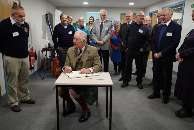 Charles signs the visitors' book.
