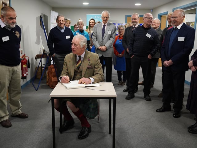 Charles signs the visitors' book.