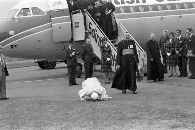 Pope John Paul II does his traditional kissing of the tarmac when he lands at Turnhouse Airport as Cardinal Gray looks on.