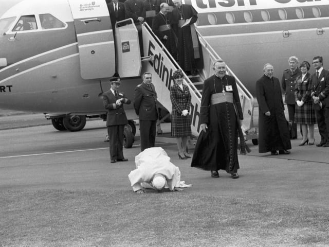 Pope John Paul II does his traditional kissing of the tarmac when he lands at Turnhouse Airport as Cardinal Gray looks on.