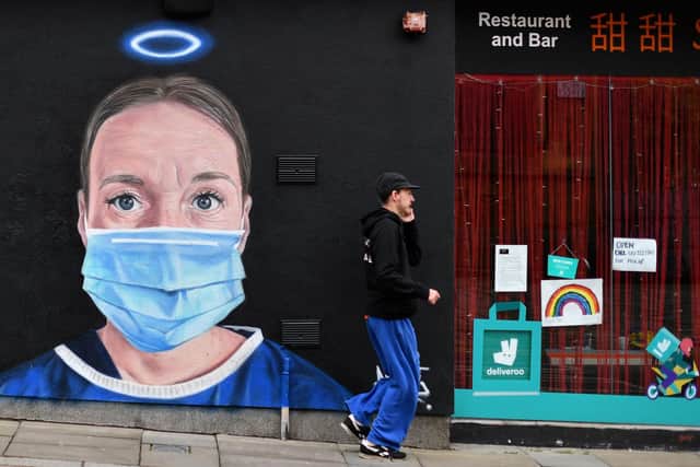A pedestrian walks past a mural in Manchester last year