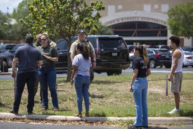 A law enforcement officer speaks with people outside Uvalde High School after shooting a was reported earlier in the day at Robb Elementary School)