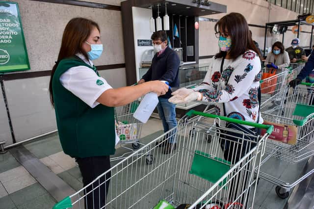 A shopper wearing gloves gets them sprayed with hand-sanitiser as a precaution against Covid (Picture: Claudio Santana/Getty Images)