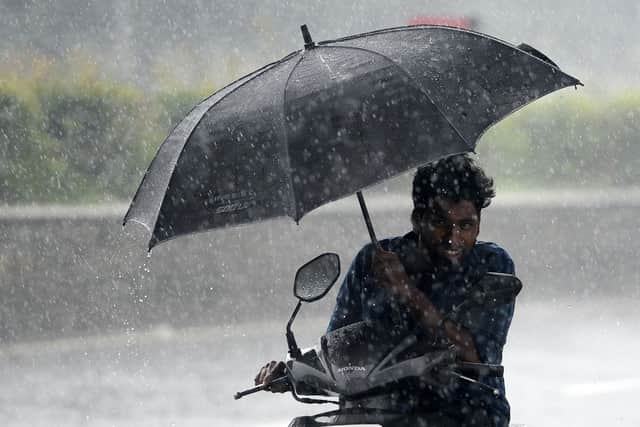 A motorist shelters under an umbrella while riding along a road during heavy monsoon rainfall in Chennai. Picture: Arun Sankar/AFP via Getty Images