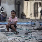 A Palestinian boy sits near buildings hit by Israeli airstrikes in the Jabaliya refugee camp, northern Gaza Strip, (Picture: Khalil Hamra/AP)
