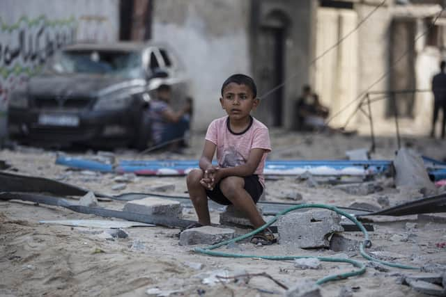 A Palestinian boy sits near buildings hit by Israeli airstrikes in the Jabaliya refugee camp, northern Gaza Strip, (Picture: Khalil Hamra/AP)