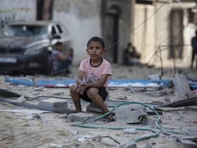A Palestinian boy sits near buildings hit by Israeli airstrikes in the Jabaliya refugee camp, northern Gaza Strip, (Picture: Khalil Hamra/AP)