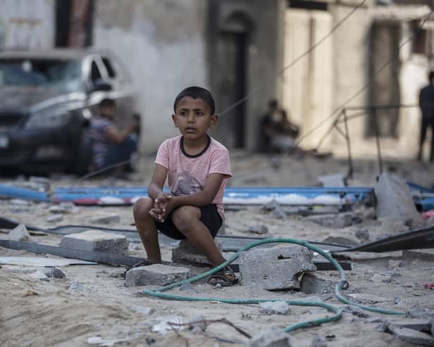 A Palestinian boy sits near buildings hit by Israeli airstrikes in the Jabaliya refugee camp, northern Gaza Strip, (Picture: Khalil Hamra/AP)