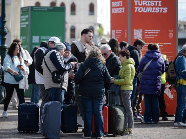 Tourists stand as they wait to pass controls in front of the Santa Lucia railway station in Venice. Visitors entering the UNESCO World Heritage site for one day have to buy a five-euro ticket from today.