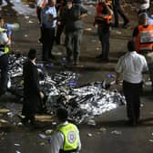 Ultra-Orthodox Jewish men stand next to covered bodies after dozens of people were killed and others injured after a grandstand collapsed in Meron, Israel, where tens of thousands of people were gathered to celebrate the festival of Lag Ba'omer at the site in northern Israel. Photo by David COHEN / JINI PIX / AFP) / Israel OUT (Photo by DAVID COHEN/JINI PIX/AFP via Getty Images)