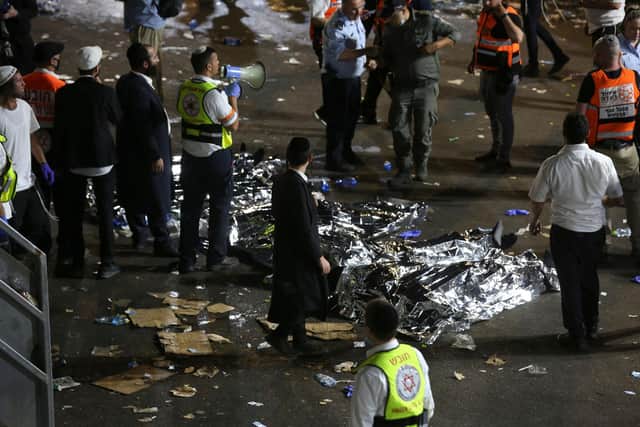 Ultra-Orthodox Jewish men stand next to covered bodies after dozens of people were killed and others injured after a grandstand collapsed in Meron, Israel, where tens of thousands of people were gathered to celebrate the festival of Lag Ba'omer at the site in northern Israel. Photo by David COHEN / JINI PIX / AFP) / Israel OUT (Photo by DAVID COHEN/JINI PIX/AFP via Getty Images)