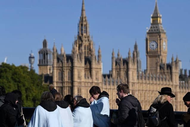 Members of the public, some wrapped in blankets, wait in the queue to pay their respects to the late Queen Elizabeth II, in London.