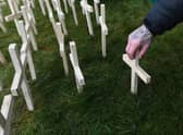 A man leaves a cross for his brother as part of a remembrance event for victims of drug deaths in Scotland (Picture: John Devlin)