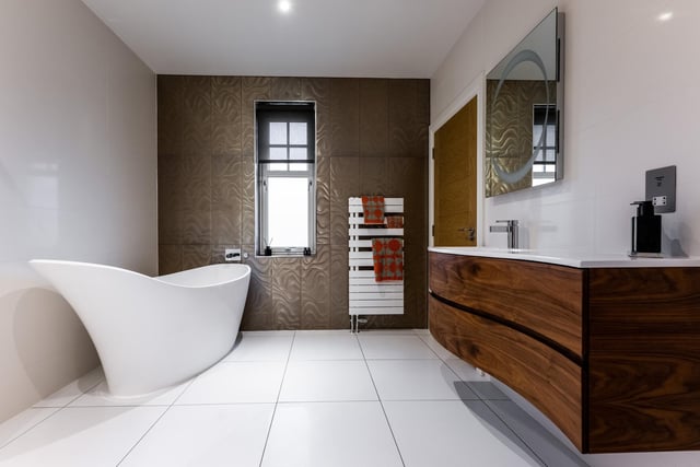 The sleek bathroom, by Laings of Inverurie, features glass tiling and a free-standing bath.