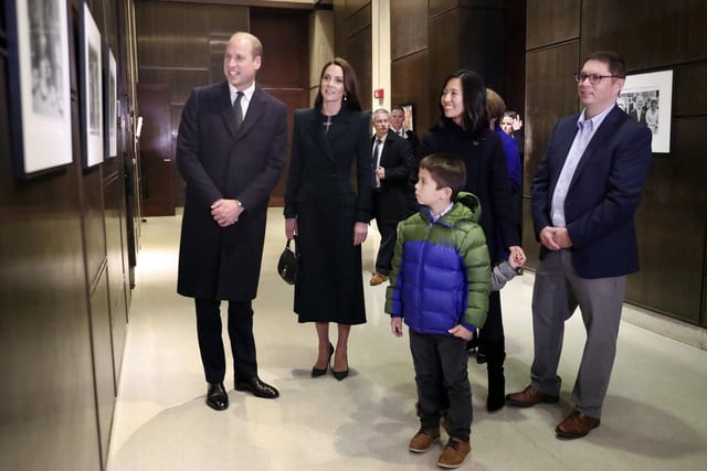 Boston Mayor Michelle Wu, right, husband Conor Perwarski, right, and sons Blaise, holds her hand, and Cass, front, show photographs of the Queen Elizabeth II's visit in 1976.