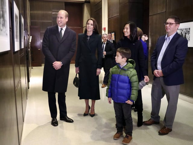 Boston Mayor Michelle Wu, right, husband Conor Perwarski, right, and sons Blaise, holds her hand, and Cass, front, show photographs of the Queen Elizabeth II's visit in 1976.
