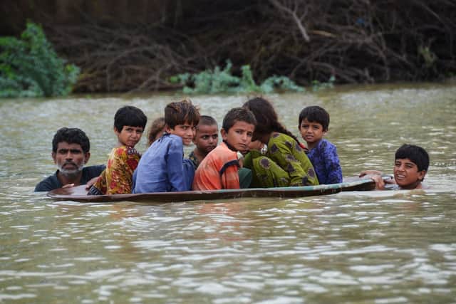 A man and a youth use a satellite dish to move children across a flooded area after heavy monsoon rains caused widespread flooding in Jaffarabad district and much of Pakistan (Picture: Fida Hussain/AFP via Getty Images)