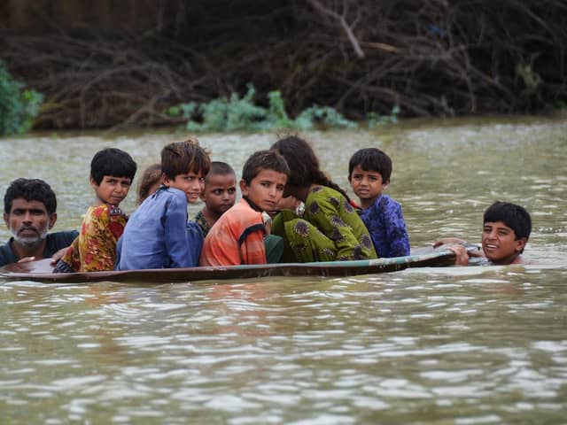A man and a youth use a satellite dish to move children across a flooded area after heavy monsoon rains caused widespread flooding in Jaffarabad district and much of Pakistan (Picture: Fida Hussain/AFP via Getty Images)