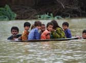 A man and a youth use a satellite dish to move children across a flooded area after heavy monsoon rains caused widespread flooding in Jaffarabad district and much of Pakistan (Picture: Fida Hussain/AFP via Getty Images)