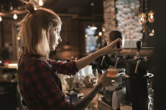A female bartender pouring beer from a tap at a bar