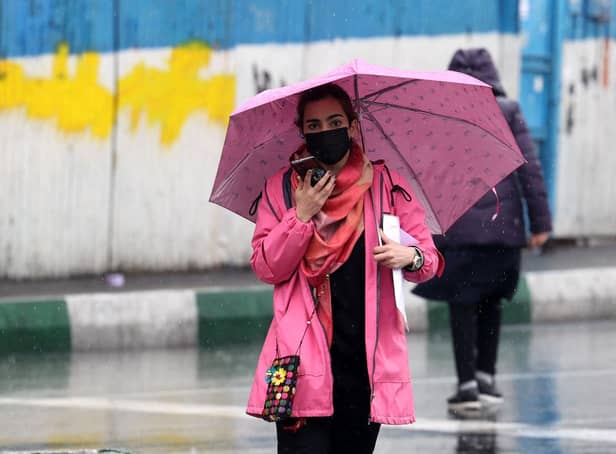An Iranian woman walks in the street on a rainy day in the capital Tehran, on the day Iran has said it has scrapped its morality police after more than two months of protests triggered by the death of Mahsa Amini following her arrest for allegedly violating the country's strict female dress code.