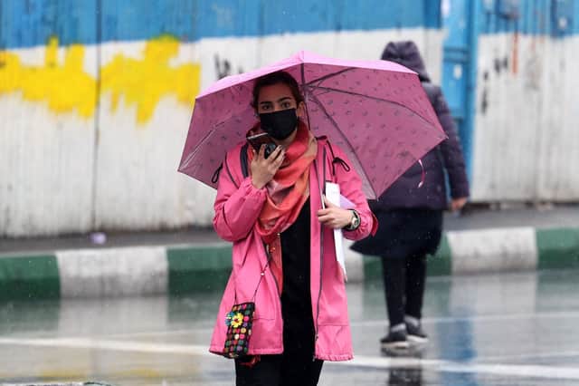 An Iranian woman walks in the street on a rainy day in the capital Tehran, on the day Iran has said it has scrapped its morality police after more than two months of protests triggered by the death of Mahsa Amini following her arrest for allegedly violating the country's strict female dress code.