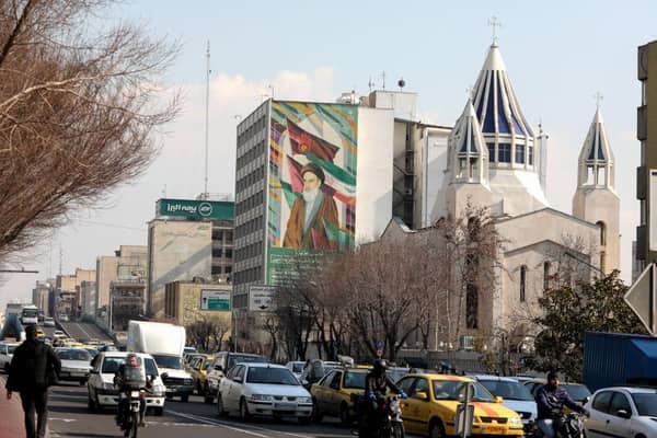 Motorists drive past a church on a main road in central Tehran with a portrait of the late founder of the Islamic republic Ayatollah Ruhollah Khomeini in the background.