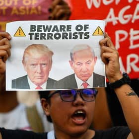 An activist holding a placard with portraits of US President Donald Trump and Israel's Prime Minister Benjamin Netanyahu at a rally condemning the US-Israeli strikes on Iran at a park in Quezon City, suburban Manila on March 2, 2026. (Picture: Ted ALJIBE / AFP via Getty Images)