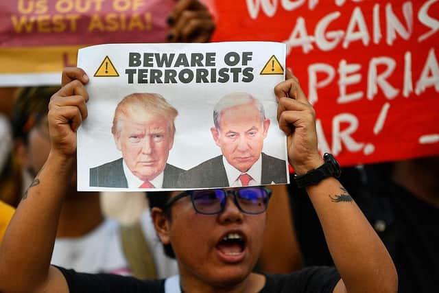 An activist holding a placard with portraits of US President Donald Trump and Israel's Prime Minister Benjamin Netanyahu at a rally condemning the US-Israeli strikes on Iran at a park in Quezon City, suburban Manila on March 2, 2026. (Picture: Ted ALJIBE / AFP via Getty Images)