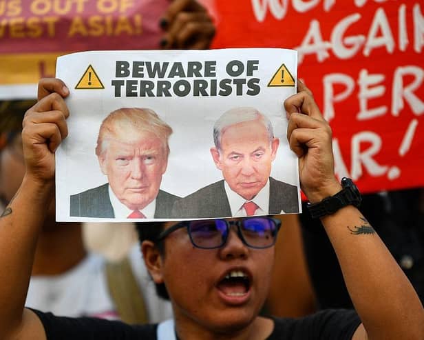 An activist holding a placard with portraits of US President Donald Trump and Israel's Prime Minister Benjamin Netanyahu at a rally condemning the US-Israeli strikes on Iran at a park in Quezon City, suburban Manila on March 2, 2026. (Picture: Ted ALJIBE / AFP via Getty Images)