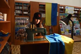 A young volunteer sews Ukrainian flags for the Ukrainian military at a library in western Ukrainian city of Lviv on April 2, 2022. Picture: YURIY DYACHYSHYN/AFP via Getty Images)