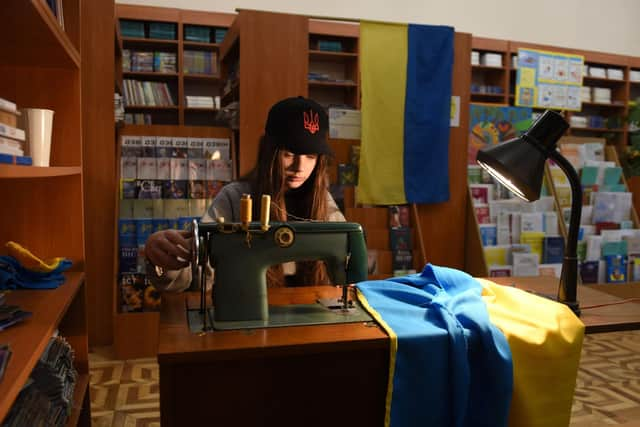 A young volunteer sews Ukrainian flags for the Ukrainian military at a library in western Ukrainian city of Lviv on April 2, 2022. Picture: YURIY DYACHYSHYN/AFP via Getty Images)