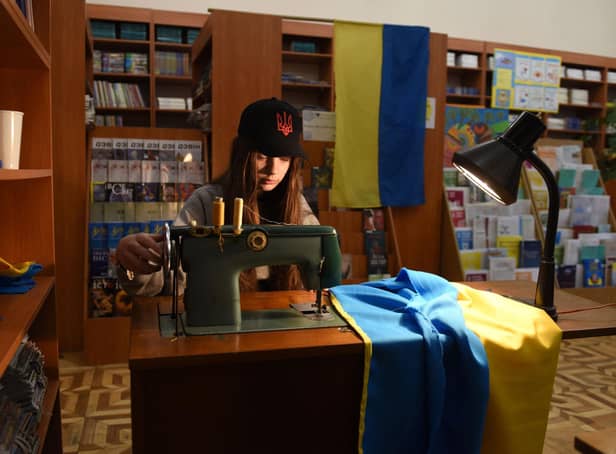 A young volunteer sews Ukrainian flags for the Ukrainian military at a library in western Ukrainian city of Lviv on April 2, 2022. Picture: YURIY DYACHYSHYN/AFP via Getty Images)