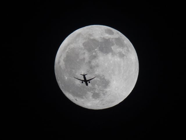 An aircraft flies past the full moon over Basra, Iraq, Sunday, May 15, 2022. (AP Photo/Nabil al-Jurani)