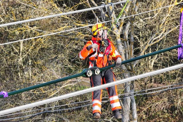 A worker on the Union Chain Bridge, standing on a cable high above the River Tweed.