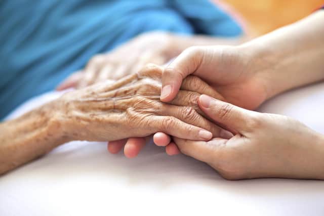 Woman holding senior woman's hand on bed