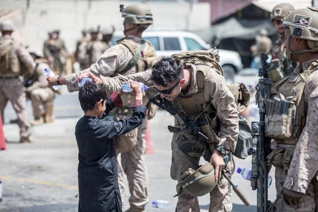 A US Marine and a child spray water at each other at Kabul Airport (Picture: Sgt Samuel Ruiz/US Marine Corps via Getty Images)