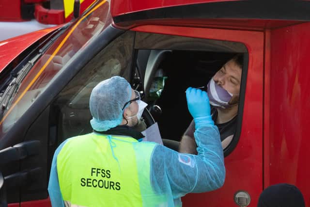 DOVER, UNITED KINGDOM - DECEMBER 24: A member of the French Federation of Rescue and First Aid swabs a lorry driver to test for Covid-19 on December 24, 2020 in Dover, United Kingdom. Travel from the UK to France is gradually resuming after being suspended due to concerns about a new strain of Covid-19. The British government deployed its Track and Trace team to administer Covid-19 tests to lorry drivers waiting to cross at Dover. (Photo by Dan Kitwood/Getty Images)