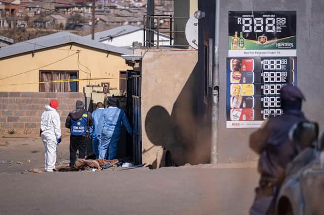 Members of the South African Police Service (SAPS) and forensic pathology services inspect the scene of a mass shooting in Soweto, South Africa, on July 10, 2022. - Fourteen people were killed during a shootout in a bar in Soweto police said on July 10, 2022.