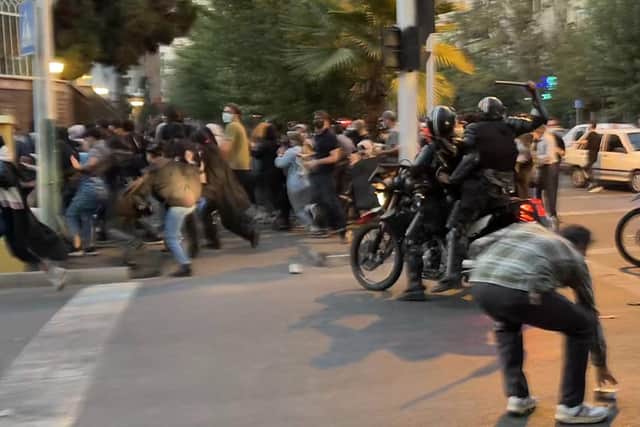 An Iranian police officer raises his baton as the authorities disperse a crowd of demonstrators protesting in Tehran about the death of Mahsa Amini (Picture obtained by AFP via Getty Images)