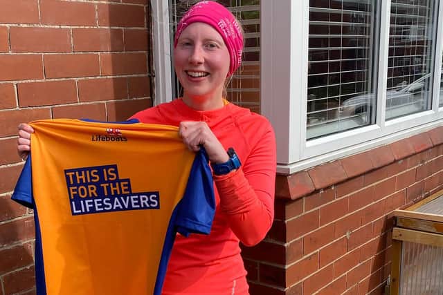 Louise Houghton holding a T-shirt made ahead of a 10k race to raise money for the RNLI. She was rescued after suffering several broken bones in an abseiling accident in Orkney. Photo: RNLI/PA Wire