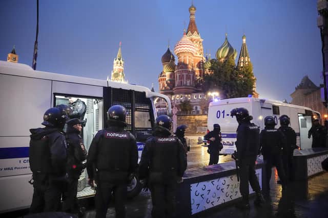 Police officers stand near police buses with detained demonstrators during a protest against a partial mobilization near Red Square with the Spasskaya Tower and St. Basil's Cathedral in the background in Moscow, Russia, Saturday, Sept. 24, 2022. (AP Photo)