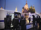 Police officers stand near police buses with detained demonstrators during a protest against a partial mobilization near Red Square with the Spasskaya Tower and St. Basil's Cathedral in the background in Moscow, Russia, Saturday, Sept. 24, 2022. (AP Photo)