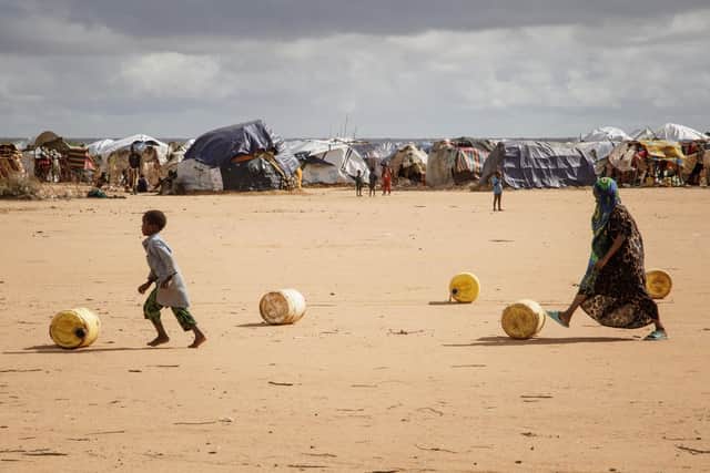 Somali children in the Dadaab refugee camp in Kenya roll water containers towards their makeshift shelter. Five consecutive seasons of failed rains have driven many Somalis to leave their country (Picture: Bobb Muriithi/AFP via Getty Images)